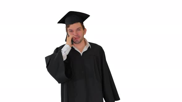 Male Graduate in Gown and Mortarboard Talking on the Phone While Walking with His Diploma on White alt