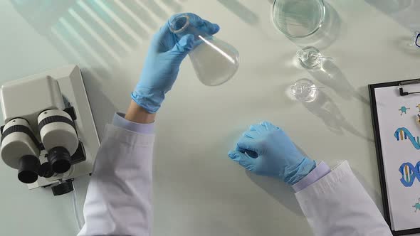 Male Laboratory Assistant Mixing Liquid Reagents, Monitoring Chemical Reaction alt