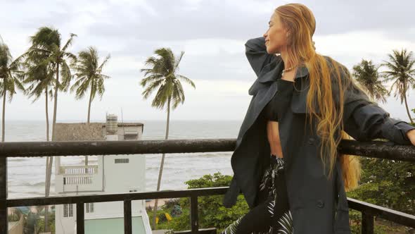 Female Model Poses on Balcony with Tropical Background of Palm Trees and the Ocean alt