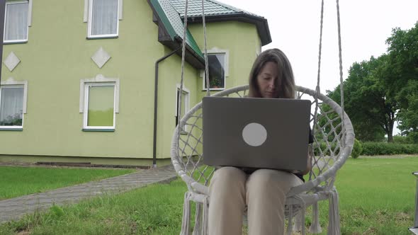 Woman in Garden Chair Using Laptop