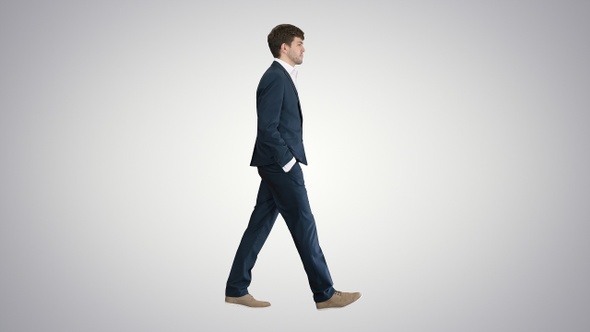 Handsome business man walking with his hands in pockets alt