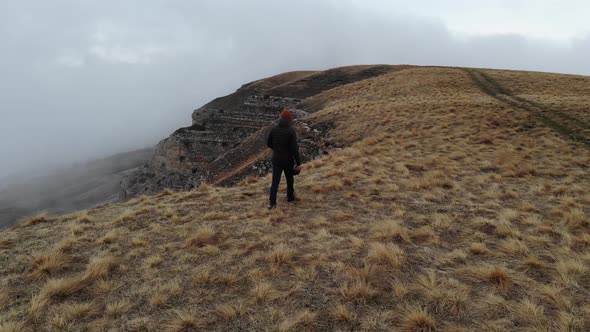 Tourist Traveler Man in Tourist Clothes Walks Along the Top of a Plateau Next to a Deep Cliff Along alt
