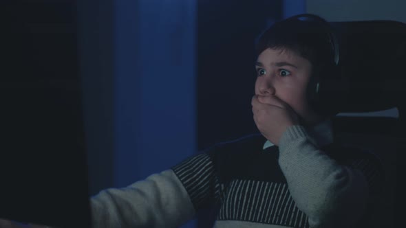 Scared Boy in Headphones Shocked By Terrible Scene While Watching Horror Video on Computer alt