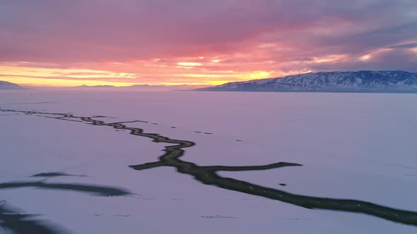 Flying backwards viewing crack in the ice on Utah Lake covered in snow alt