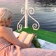 Beautiful Girl on a Raft on the Lake Sits on a Blanket and Reads a Book - VideoHive Item for Sale