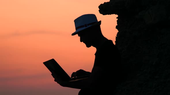Hipster with Notebook on Sunset Background