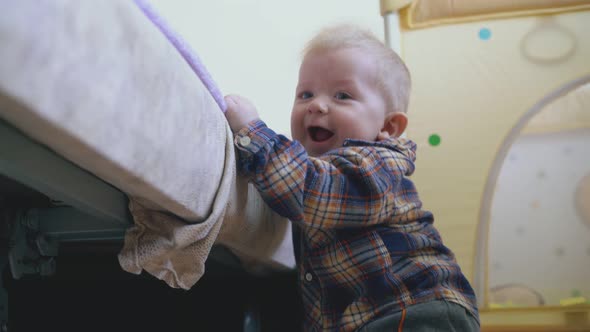 Little Baby in Shirt and Pants Plays at Large Soft Bed alt