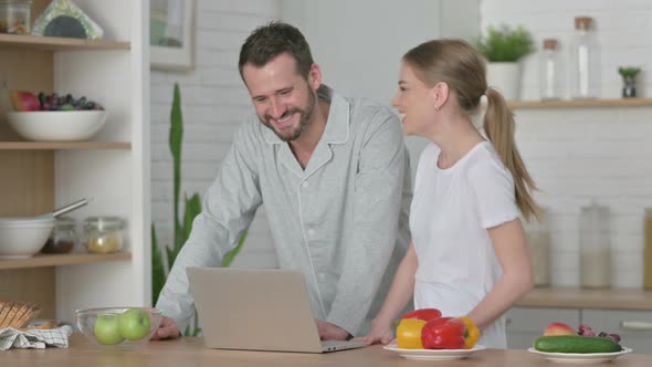 Woman and Man Doing Video Call on Laptop in Kitchen alt