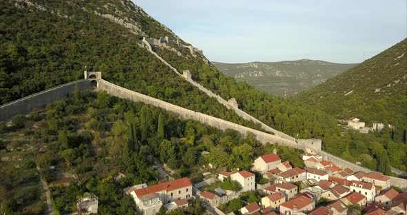 Aerial shot of Ston in Croatia, an ancient walled city, the camera follows the walls over the hills alt