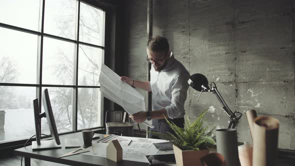 Young Architect in Stylish Loft Office Works with Documents