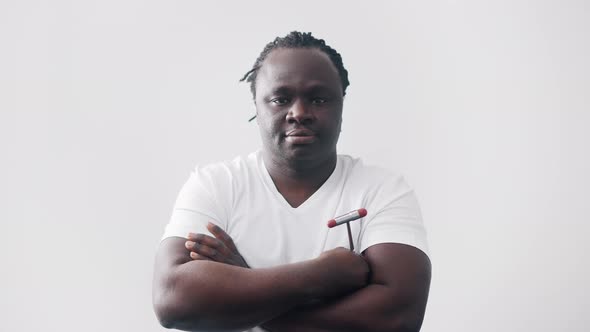 African American Black Man with Crossed Hands Over the Chest Holding Medical Reflex Hammer alt