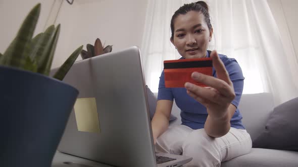 Asian businesswoman are using cards to pay for online shopping on a laptop alt