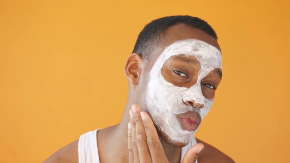 Cute African American with Problem Skin Uses a White Face Mask Isolated on a Yellow Background alt