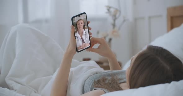 Young Girl Sick at Home Using Smartphone To Talk To Her Doctor Via Video Conference Medical App alt
