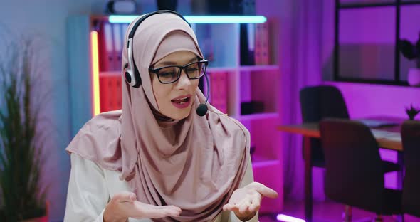 Arabic Businesswoman in Light Violet Hijab in Headset Enjoying Conversation During Video chat alt