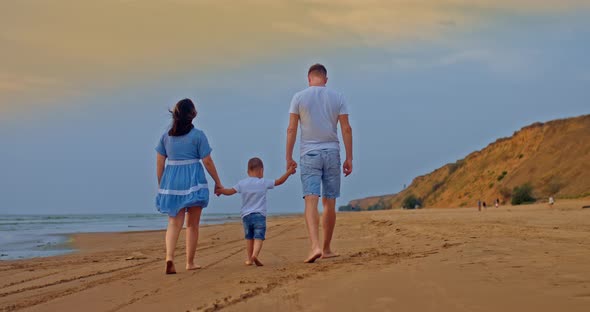 Family with a Small Child is Walking Along the Shore Walking By the Sea