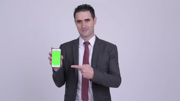 Happy Handsome Businessman Showing Phone and Giving Thumbs Up alt