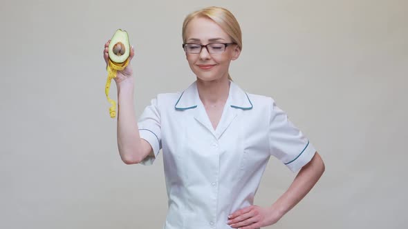 Nutritionist Doctor Healthy Lifestyle Concept - Holding Organic Avocado Fruit and Measuring Tape alt