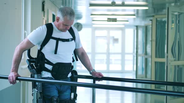 Handicapped Man is Learning to Walk in the Exoskeleton alt