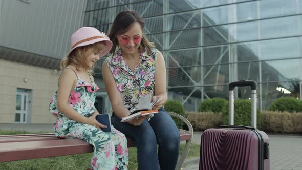 Mother and Daughter Near Airport. Woman Hold Passports and Tickets in Hand. Child and Mom Vacation alt