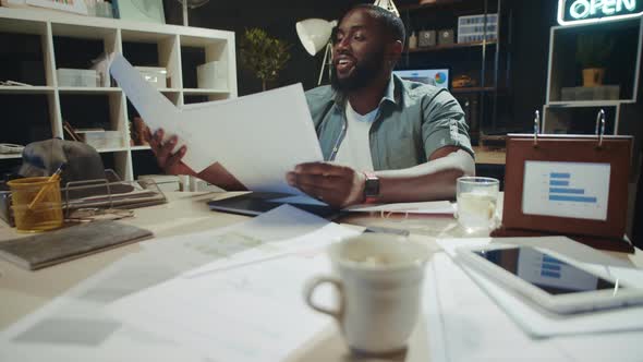 Happy African Man Enjoying Results in Office. Smiling Afro Guy Showing Thumb Up. alt
