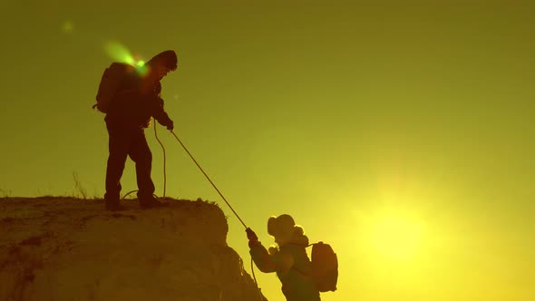 Climbers Climb Mountain on a Rope. Girl Traveler Breaks Down and Falls Off a Cliff. Teamwork of alt