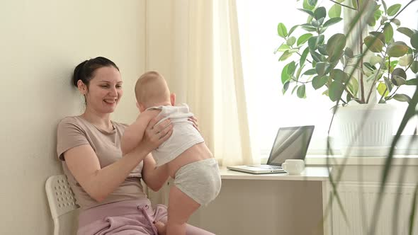 Young Single Mother Work From Home Office with Laptop Computer During Quarantine Playing with Little Baby