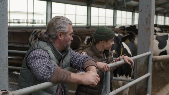 Man and Boy Chatting inside Dairy Farm Facility alt
