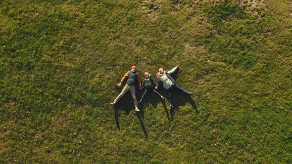 A Family of Three Father Mother and Son are Lying on the Grass in a Park alt