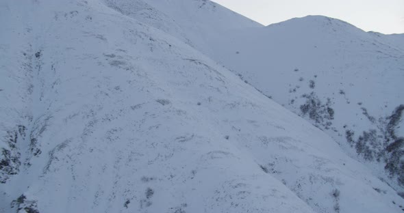 Closeup on Alaska State Trooper helicopter flying helicopter in front of mountains, drone aerial foo alt
