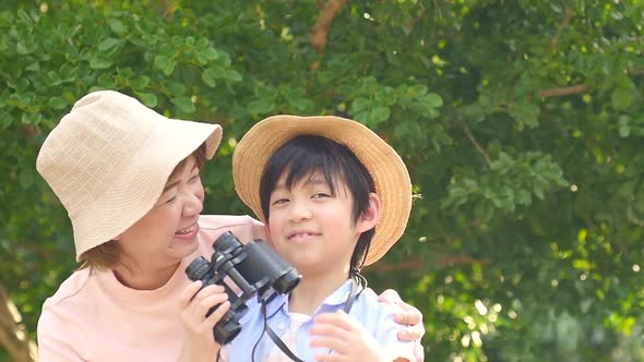 Asian Mother And Her Son Using Binocular And Pointing On Summer Day alt