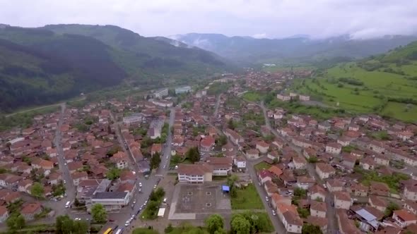 Drone  shot of a city and green land and mountain in distance alt