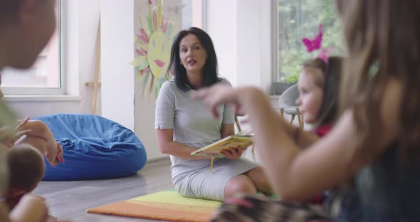 Storytime Elementary or Primary School Teacher Reading a Story to a Group of Children in a Daycare alt