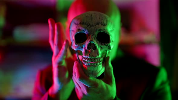 Old Human Skull in Hands of Strange Man in Neon Lights Mysterious Portrait alt