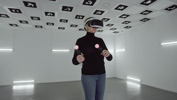 Young Woman Is Wearing Vr Headset and Making Hand Gestures with Controllers in an Empty Room Full of