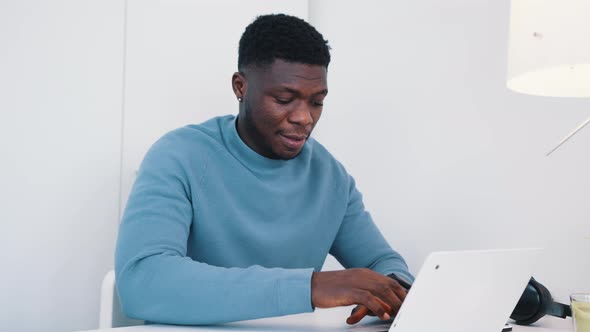 African American Black Man Sitting at the Table in Front of a Laptop Working alt