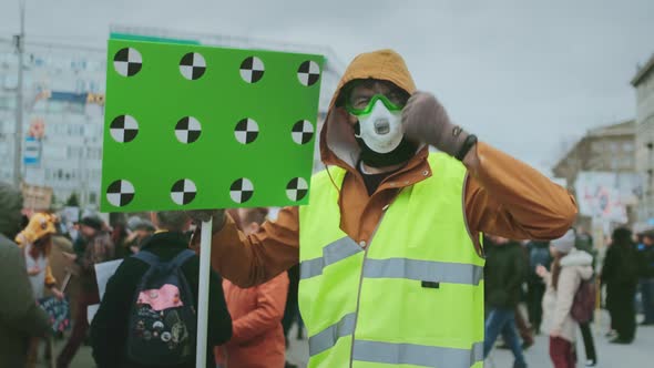 Gasmask Face. Anger People in Green Vests Yell and Wave Hand. Man in a Gas Mask alt
