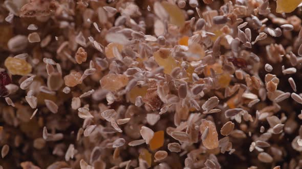 Nuts, seeds and dried fruit fly after being exploded against black background. Slow Motion. alt