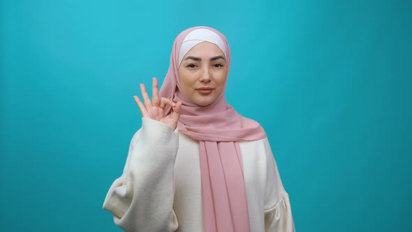Young Muslim Woman in Hijab Look Camera Approvingly Say Wow It is Ok Showing Okay Sign Gesture