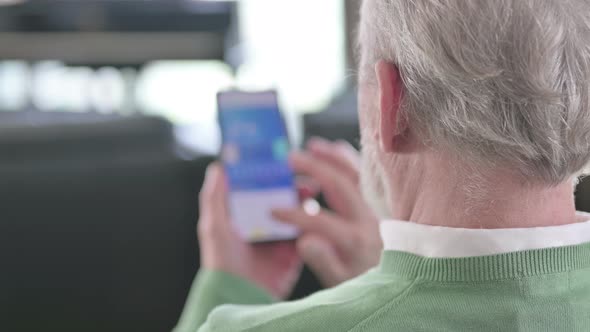 Rear View of Old Man Using Smartphone alt