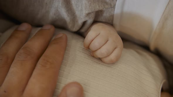 Father Touching and Holding Hands with His Newborn Baby Daughter alt