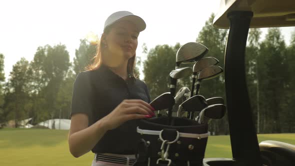 Professional woman golf player choosing the golf club from the bag. alt