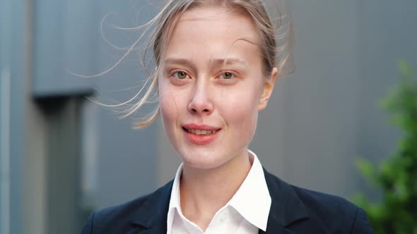 Young Female is standing near Office Building, textng Messages on her Smartphone. alt