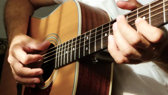 The Musician Plays with His Fingers on a Yellow Acoustic Guitar, a Ray of Light Falls on the Fingers alt