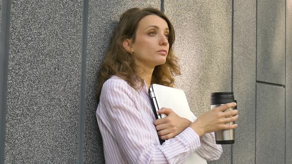 Female Portrait of Young Woman with Silver Laptop and Cup of Coffee Waiting for a Meeting Near Dark alt