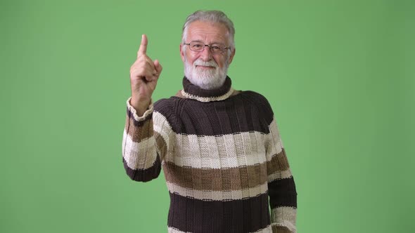 Handsome Senior Bearded Man Wearing Warm Clothing Against Green Background alt