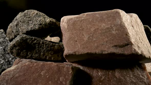 Pieces of Solid Rough Granite Stone Rotating Against a Black Studio Background alt
