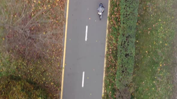 Aerial view Child riding bicycle in autumn park. Active sport family leisure. alt