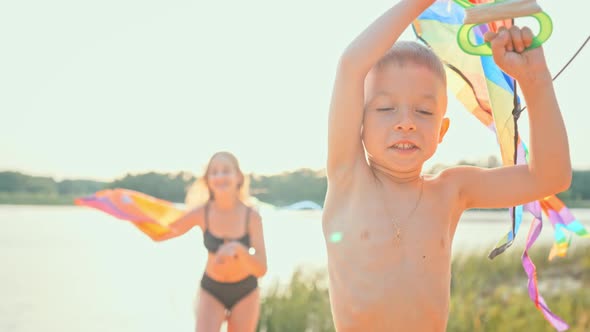 Two Children Running Along Beach in Summer with Kite Flying in Wind alt