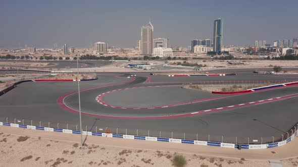 Aerial view of empty Dubai Autodrome race track hairpin turn, Dubai skyline